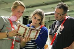 Drei Personen lesen ein Dokument in der Sporthalle.