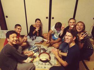 Zeigt eine Gruppe Jugendlicher beim Essen auf dem Boden sitzend